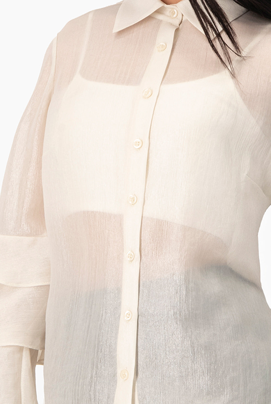 Blusa natural de manga larga con olanes y botones frontales.